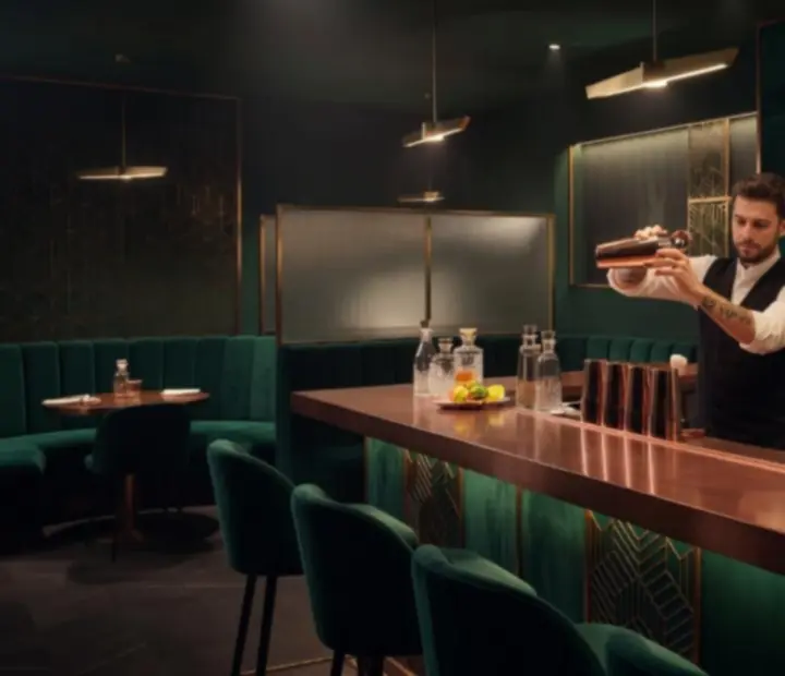 Moody Australian cocktail bar with emerald lighting and guests seated at the counter